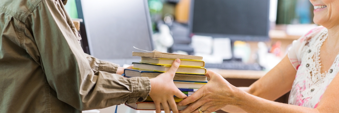 Librarian handing off stack of books to patron